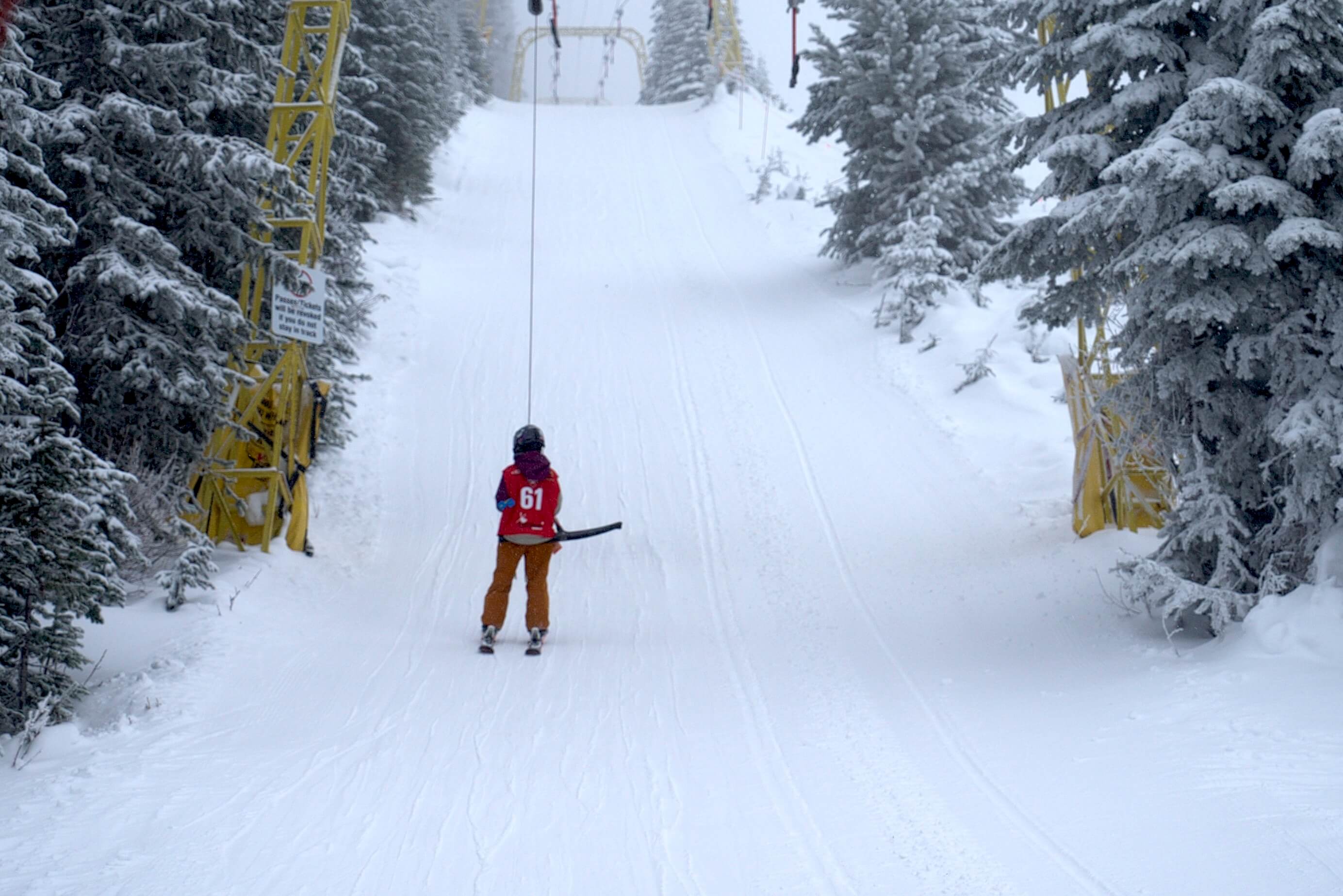 Kid skiing up the drag lift