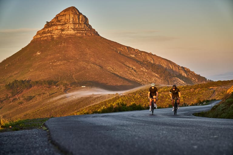 2 road cyclists riding next to table mountain